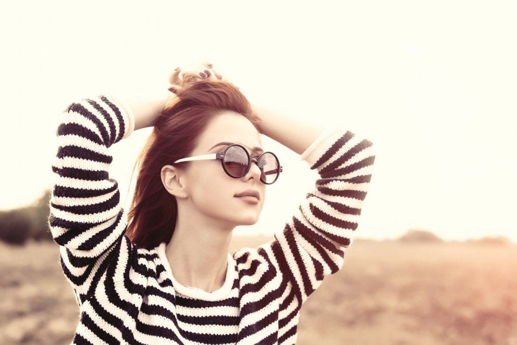 Young woman wearing shades with hands on head